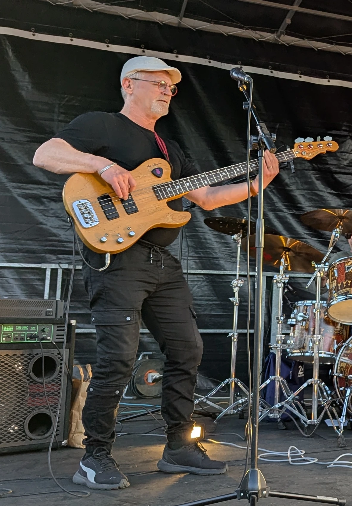Valentin avec sa basse couleur bois devant la batterie sur scène