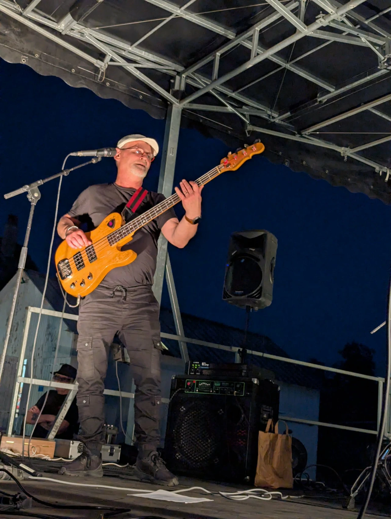Valentin joue de la basse sur une scène extérieure au crépuscule